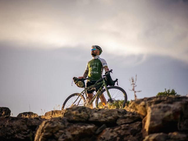 A mountain biker pausing at a summit at sunset