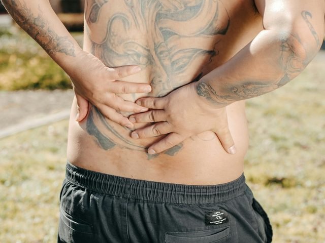 A person pressing their lower back and flank in pain